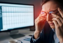 Frau mit zusammengekniffenen Augen und Brille vor Bildschirm