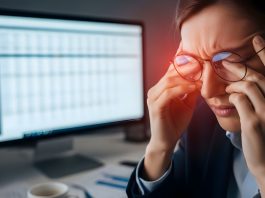 Frau mit zusammengekniffenen Augen und Brille vor Bildschirm