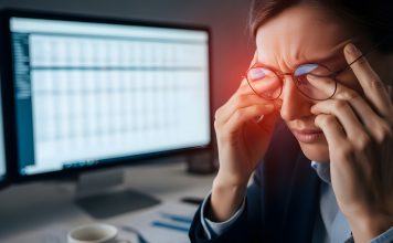 Frau mit zusammengekniffenen Augen und Brille vor Bildschirm