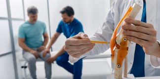 Zwei Fachpersonen beraten Patienten zu Behandlung seiner Knieverletzung