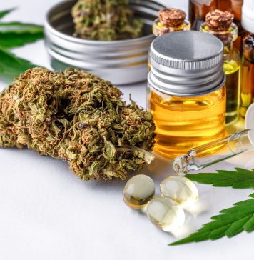 Auf einem weißen Tisch stehen und liegen verschiedene CBD Produkte, wie CBD Öl, CBD Blüten und CBD Kapseln.