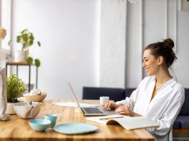 Frau sitzt im Wohnzimmer am Schreibtisch und arbeitet.