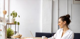 Frau sitzt im Wohnzimmer am Schreibtisch und arbeitet.