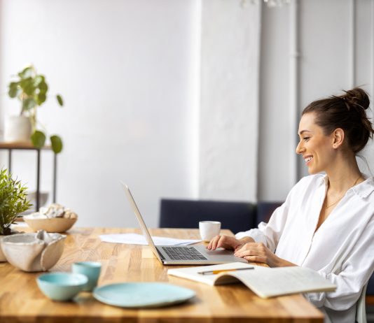 Frau sitzt im Wohnzimmer am Schreibtisch und arbeitet.