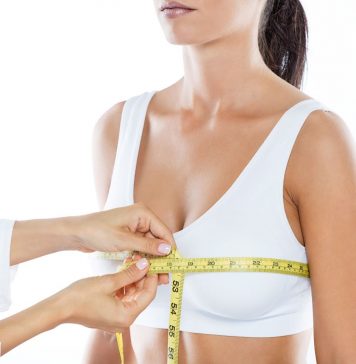 Ärztliches Fachpersonal misst den Brustumfang einer Frau mit Maßband zur Vorbereitung auf eine Brustverkleinerung oder medizinische Beratung. Fokus auf Anpassung der Brustgröße und körperliche Gesundheit.