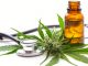 Cannabisblüte, Hanfblätter, braunes Ölfläschchen und Stethoskop als Symbolbild für medizinisches Cannabis und mögliche Anwendungen in der Schmerztherapie.