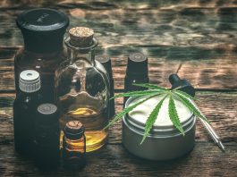 Verschiedene CBD-Produkte auf Holztisch, darunter Ölflaschen, Cremedose mit Hanfblatt und Pipette – Symbol für natürliche Anwendungen von Cannabidiol zur Unterstützung von Gesundheit und Wohlbefinden.