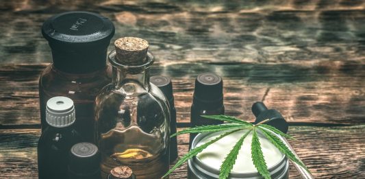 Verschiedene CBD-Produkte auf Holztisch, darunter Ölflaschen, Cremedose mit Hanfblatt und Pipette – Symbol für natürliche Anwendungen von Cannabidiol zur Unterstützung von Gesundheit und Wohlbefinden.