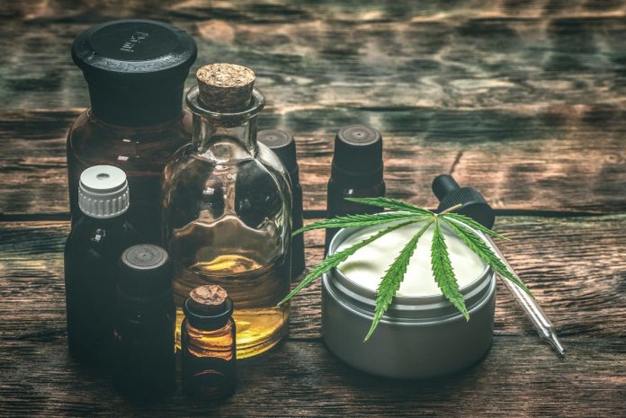 cbd_natuerlicher_helfer_gesundheit_wohlbefinden Verschiedene CBD-Produkte auf Holztisch, darunter Ölflaschen, Cremedose mit Hanfblatt und Pipette – Symbol für natürliche Anwendungen von Cannabidiol zur Unterstützung von Gesundheit und Wohlbefinden.