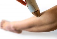 Frau wendet ein IPL-Gerät zur dauerhaften Haarentfernung am Unterschenkel an. Nahaufnahme der Behandlung, Fokus auf Haut und Handgerät für glatte, haarfreie Beine.