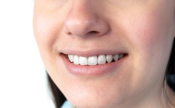 Nahaufnahme eines lächelnden Mundes mit weißen, gepflegten Zähnen und gesundem Zahnfleisch; zeigt ein natürliches Lächeln und dient zur Veranschaulichung von Mundgesundheit und guter Mundhygiene.