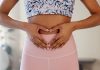 Frau formt mit den Händen ein Herz über dem Unterbauch – Symbol für ein gesundes Bauchgefühl, Darmgesundheit und ganzheitliches Wohlbefinden.