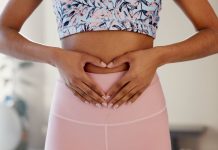 Frau formt mit den Händen ein Herz über dem Unterbauch – Symbol für ein gesundes Bauchgefühl, Darmgesundheit und ganzheitliches Wohlbefinden.