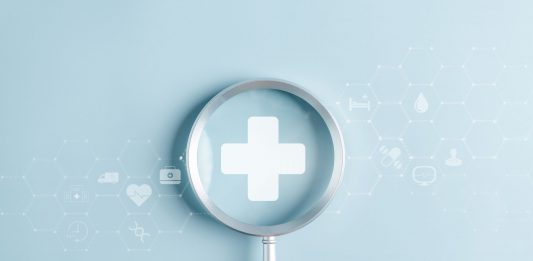 Gesundheitsvorsorge als Schlüssel zu mehr Lebensqualität Hand hält eine Lupe über einem medizinischen Kreuz, umgeben von digitalen Gesundheitssymbolen als Motiv für Gesundheitsvorsorge und Prävention.