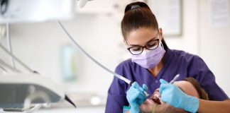 Zahnmedizinische Fachkraft behandelt einen Patienten im Behandlungsstuhl als Illustration zur Vorbereitung auf einen geplanten Zahnarzteingriff.