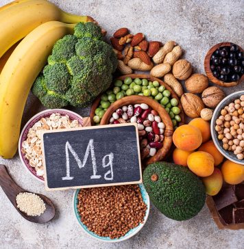 Magnesiumreiche Lebensmittel wie Bananen, Nüsse, Hülsenfrüchte, Brokkoli und dunkle Schokolade liegen neben einer Tafel mit Mg-Symbol.