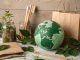 Nachhaltige Produkte aus Naturmaterialien: Globus, Bambuszahnbürsten, Papierverpackung und Pflanzen symbolisieren umweltfreundlichen Lebensstil und bewussten Konsum.