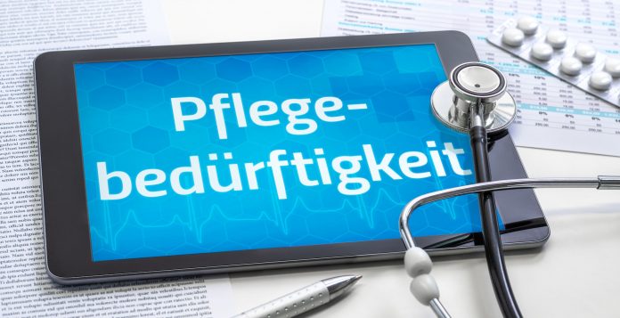 Tablet mit dem Schriftzug „Pflegebedürftigkeit“, Stethoskop, Medikamentenblister und Dokumente als Symbol für Pflegegrad und Pflegeleistungen.