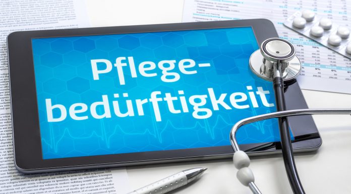 Tablet mit dem Schriftzug „Pflegebedürftigkeit“, Stethoskop, Medikamentenblister und Dokumente als Symbol für Pflegegrad und Pflegeleistungen.
