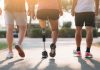 Drei Menschen joggen bei warmem Sonnenlicht auf einem Parkweg; die Person in der Mitte läuft mit einer Unterschenkelprothese.