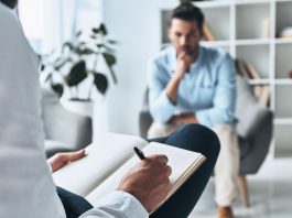 Trauma und Angst nachhaltig überwinden: Wie innovative Therapien das Gehirn neu vernetzen Psychotherapeutische Sitzung: Ein Mann spricht mit einem Therapeuten, der Notizen macht. Thema sind Trauma, Angststörungen und moderne Traumatherapie in ruhiger Praxisumgebung.
