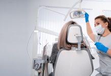 Vorsorge ist besser als Nachsorge – wie wichtig regelmäßige Besuche beim Zahnarzt sind Zahnärztin mit Maske und Handschuhen bereitet in einer hellen Praxis die zahnärztliche Untersuchung einer Patientin auf dem Behandlungsstuhl vor.