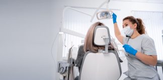 Vorsorge ist besser als Nachsorge – wie wichtig regelmäßige Besuche beim Zahnarzt sind Zahnärztin mit Maske und Handschuhen bereitet in einer hellen Praxis die zahnärztliche Untersuchung einer Patientin auf dem Behandlungsstuhl vor.