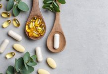 Omega-3-Kapseln und Nahrungsergänzungsmittel auf Holzlöffeln mit grünen Blättern auf hellem Hintergrund. Symbolbild für Fischöl, EPA, DHA, Omega-3-Präparate und Gesundheitsvorsorge.