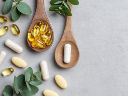 Welches Omega 3 sollte ich kaufen? Omega-3-Kapseln und Nahrungsergänzungsmittel auf Holzlöffeln mit grünen Blättern auf hellem Hintergrund. Symbolbild für Fischöl, EPA, DHA, Omega-3-Präparate und Gesundheitsvorsorge.