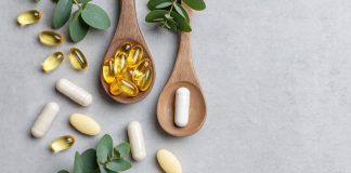 Omega-3-Kapseln und Nahrungsergänzungsmittel auf Holzlöffeln mit grünen Blättern auf hellem Hintergrund. Symbolbild für Fischöl, EPA, DHA, Omega-3-Präparate und Gesundheitsvorsorge.