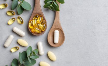 Omega-3-Kapseln und Nahrungsergänzungsmittel auf Holzlöffeln mit grünen Blättern auf hellem Hintergrund. Symbolbild für Fischöl, EPA, DHA, Omega-3-Präparate und Gesundheitsvorsorge.