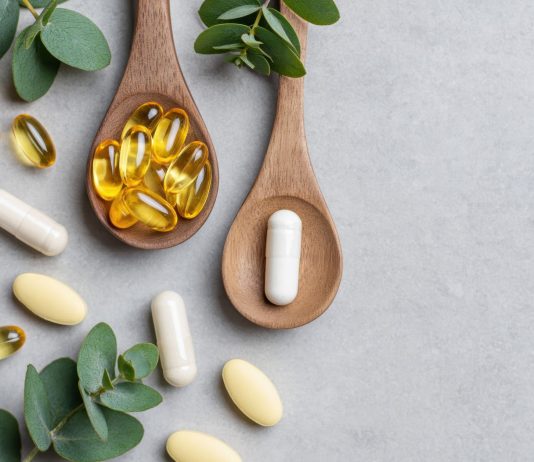 Welches Omega 3 sollte ich kaufen? Omega-3-Kapseln und Nahrungsergänzungsmittel auf Holzlöffeln mit grünen Blättern auf hellem Hintergrund. Symbolbild für Fischöl, EPA, DHA, Omega-3-Präparate und Gesundheitsvorsorge.