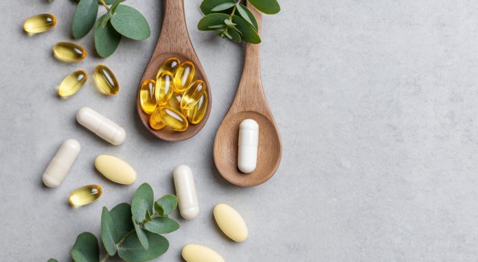 welches-omega-drei-kaufen Omega-3-Kapseln und Nahrungsergänzungsmittel auf Holzlöffeln mit grünen Blättern auf hellem Hintergrund. Symbolbild für Fischöl, EPA, DHA, Omega-3-Präparate und Gesundheitsvorsorge.